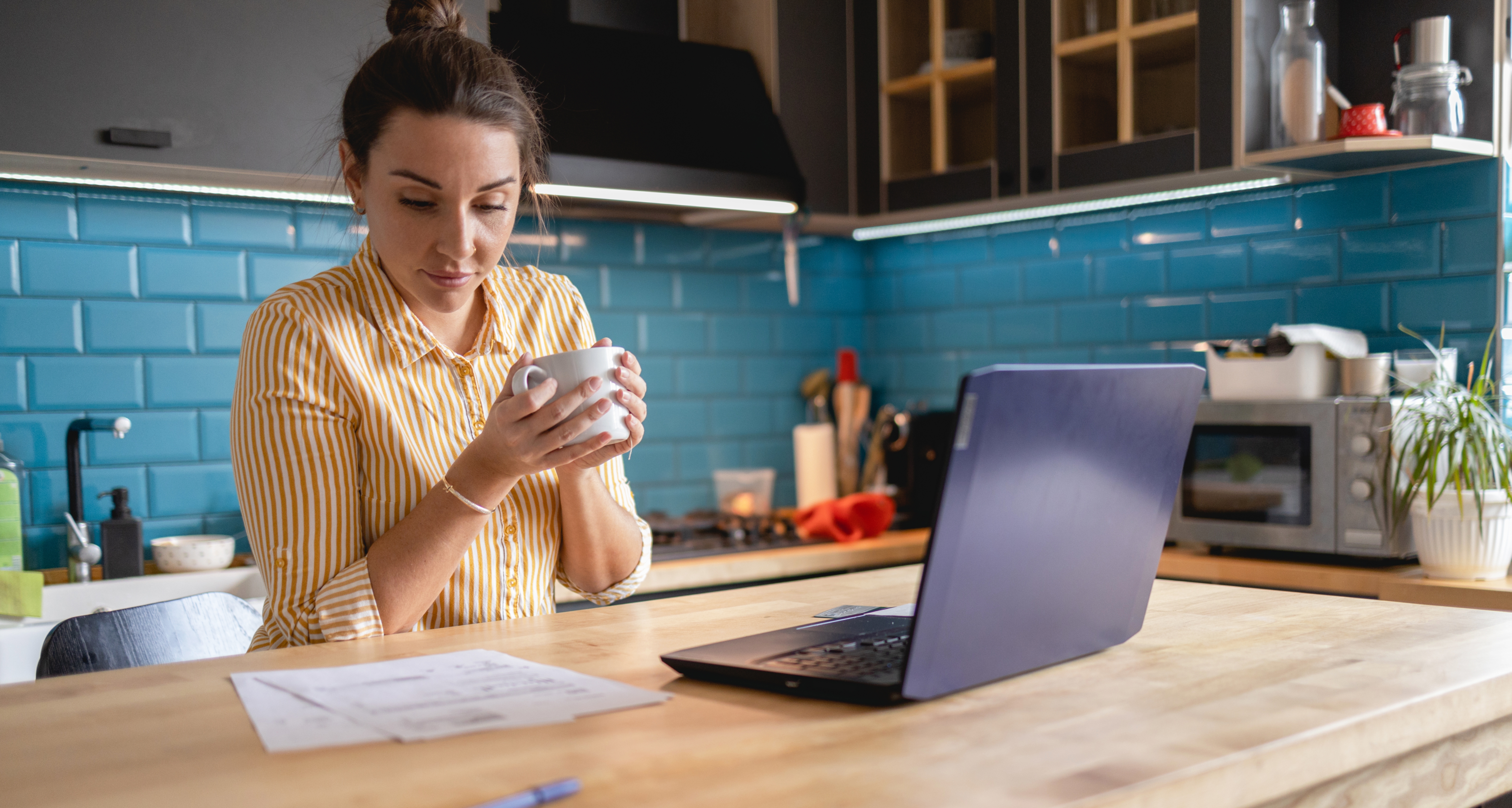 Woman sitting in kitchen looking at a piece of paper