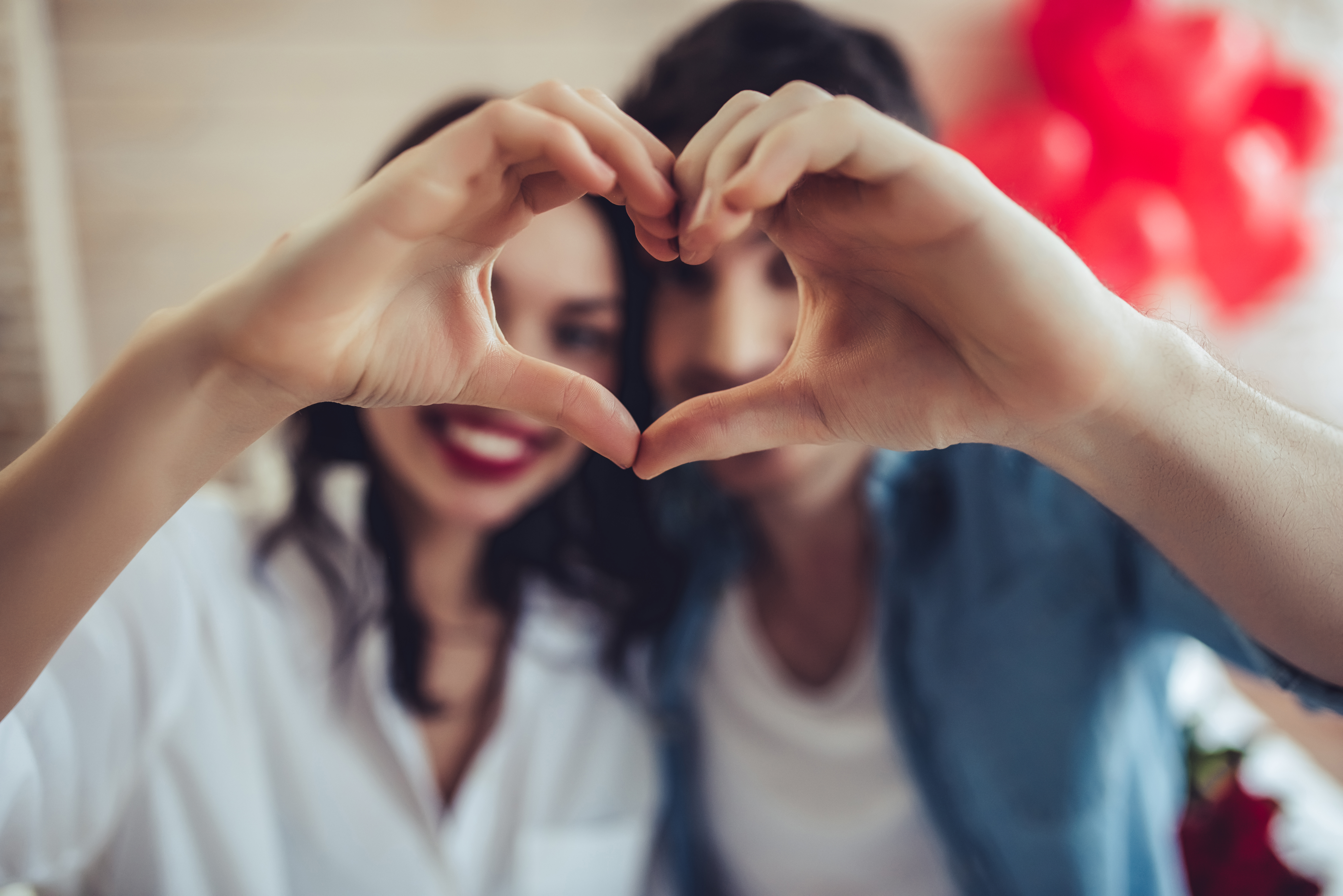 A man and a woman having each of their hand to form the shape of heart